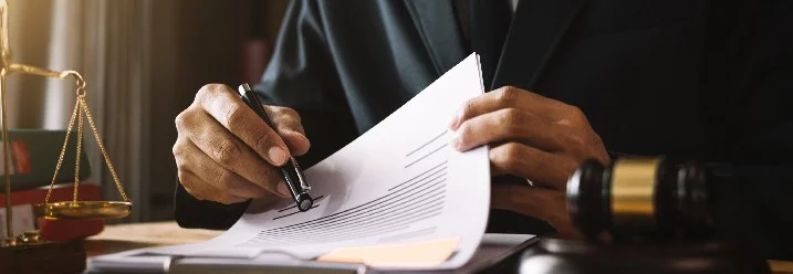 Person mit Stift zeigt auf ein Dokument